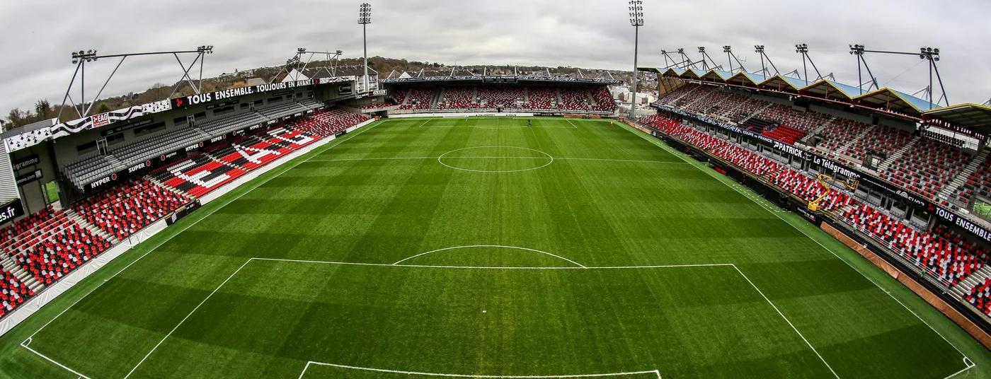 Panoramic view of the Stade du Roudourou in Guingamp, with red and black stands around the pitch